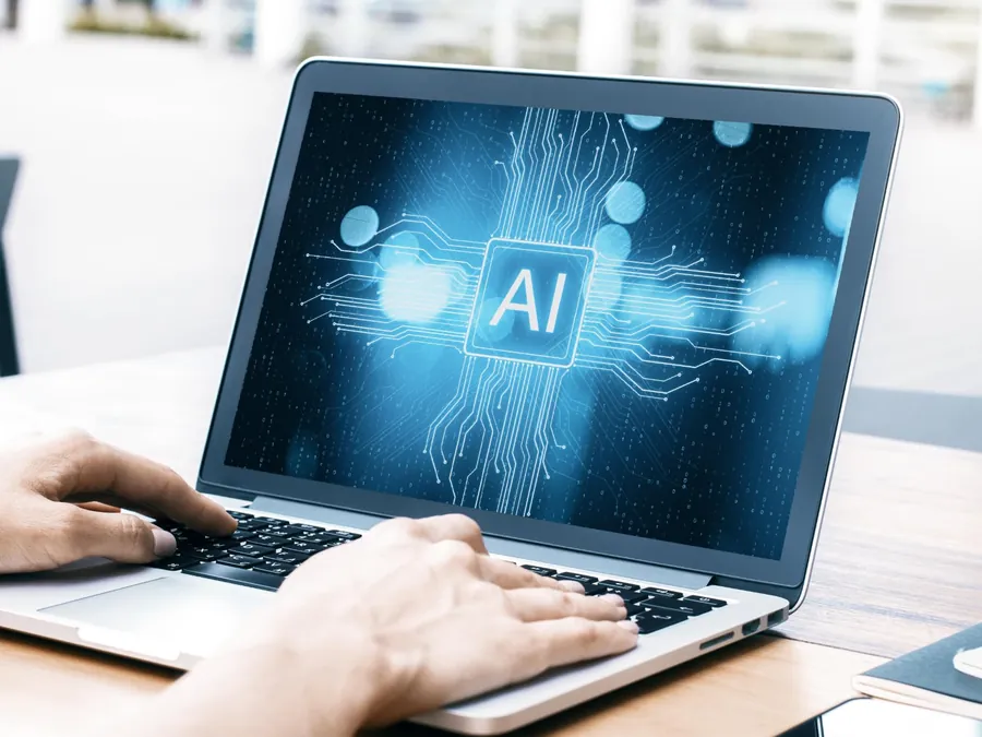 Manos sobre una notebook con una interfaz de inteligencia artificial en pantalla